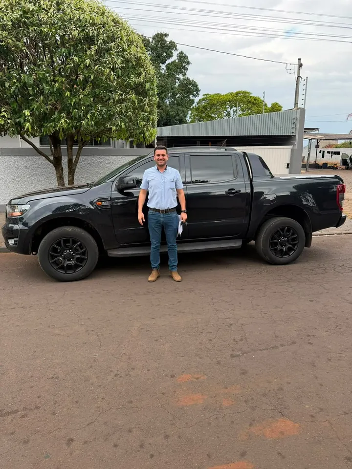 Cliente de camisa azul em frente à picape preta que comprou na LV