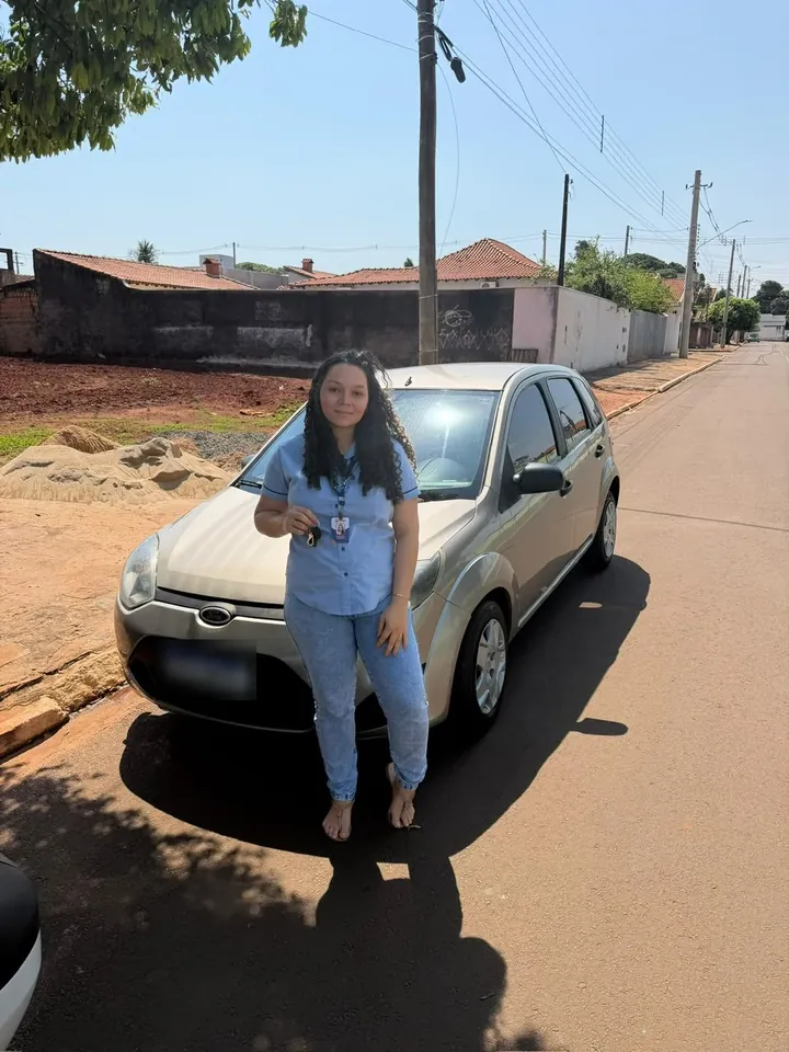 Cliente com a chave na mão em frente ao hatch dourado que comprou na LV