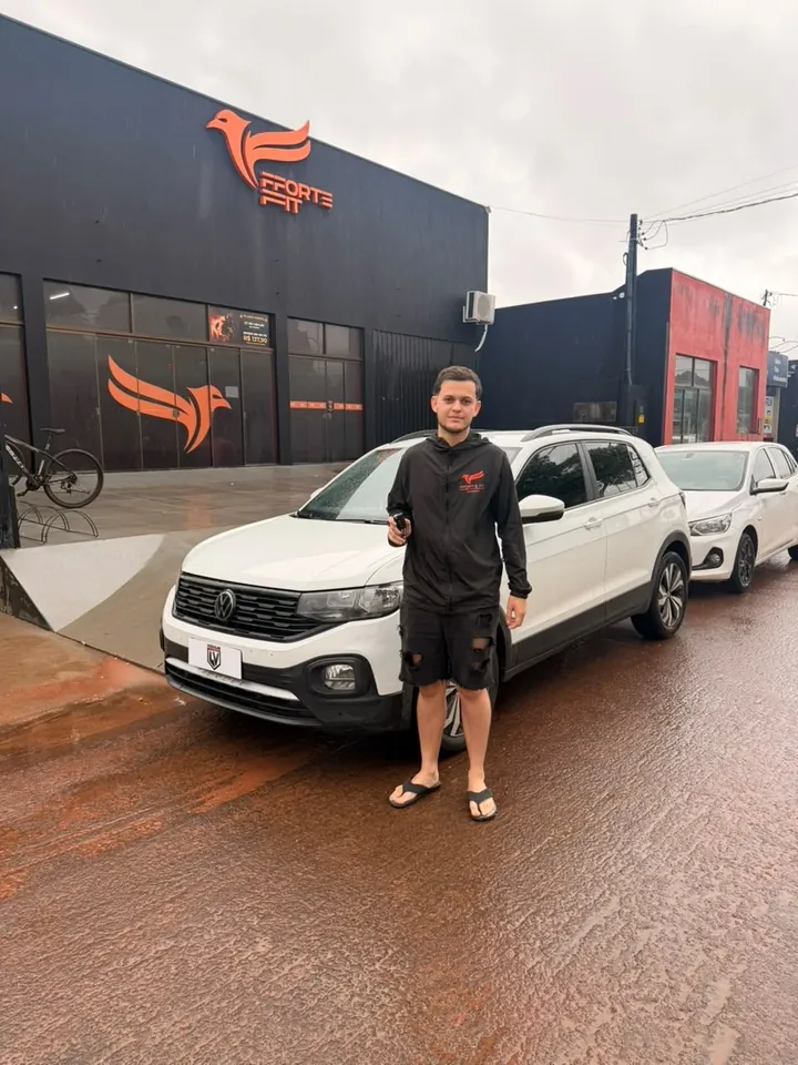 Cliente segurando a chave do SUV branco que comprou na LV, com a placa da LV Veículos